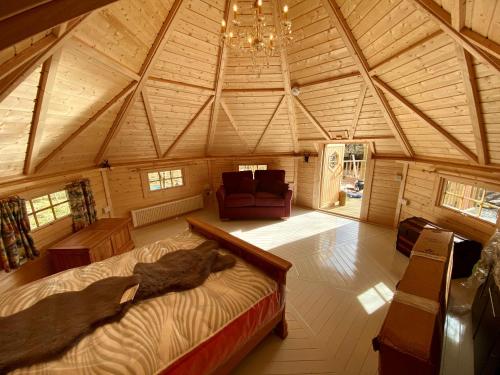 Woodland Lodge Mither Tap في Kintore: غرفة كبيرة بها سرير واريكة في كابينة