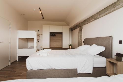 una camera con due letti con lenzuola bianche di De Balloo, vakantiehuis met sauna en jacuzzi a Zuienkerke