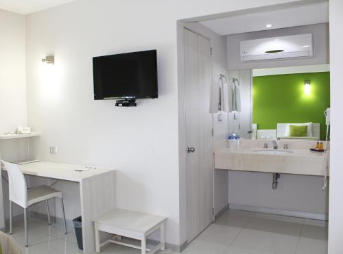 a bathroom with a sink and a desk with a tv on the wall at SC HOTEL in Xalapa