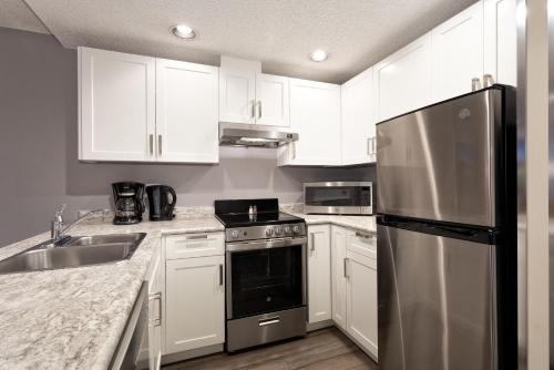 a kitchen with white cabinets and a stainless steel refrigerator at Lake Placid Lodge by Whiski Jack in Whistler