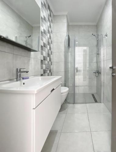 a white bathroom with a sink and a shower at Azize Palas Apart Otel in Çeşme