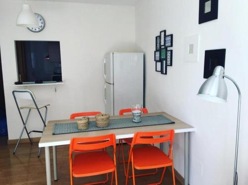 eine Küche mit einem Tisch mit orangefarbenen Stühlen und einem Kühlschrank in der Unterkunft La Brisa Malagueta in Málaga