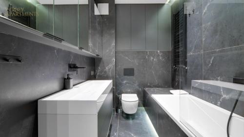 ein Badezimmer mit zwei Waschbecken, einer Badewanne und einem WC in der Unterkunft Apartament Chmielny River View - Granaria - Comfy Apartments in Danzig