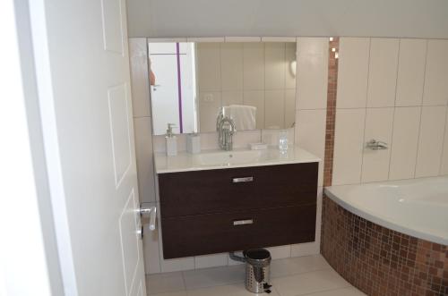 a bathroom with a sink and a mirror and a tub at La Petite Ecole in Marciac