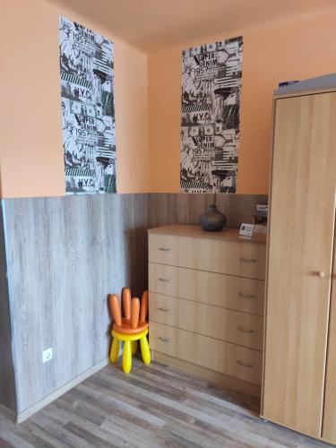 a childrens room with a dresser and a yellow chair at Jázmin Apartman in Szeged