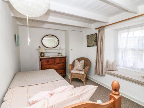 ein Schlafzimmer mit einem Bett und einem Stuhl und einem Fenster in der Unterkunft Mural Cottage in Mousehole