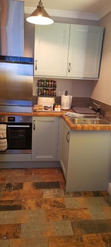 a kitchen with white cabinets and a sink and a stove at The lodge in Blackwood