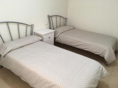 a room with two twin beds and a white wall at Residencial Alhambras1 in Murcia