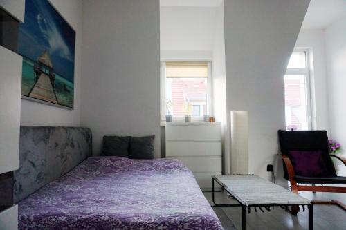 a bedroom with a bed and a chair and a table at Apartment Studio BOSSANOVA in Bydgoszcz