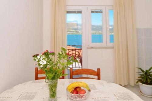 stół z miską owoców i wazonem kwiatów w obiekcie Apartments Sima - 100m from beach w Trogirze
