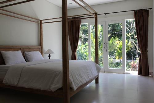 乌布珠玛酒店的一间卧室，里面有一张床和一扇大窗户。