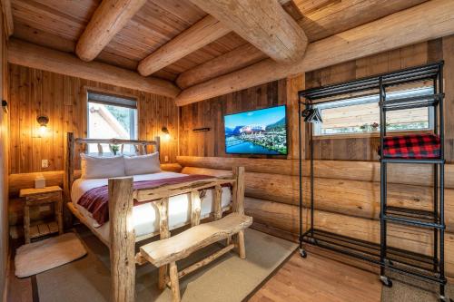 a bedroom in a log cabin with a bed and a tv at Boulder Mountain Resort in Revelstoke