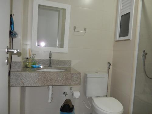 a bathroom with a toilet and a sink and a window at Flat entre mar e lagoa II in Arraial do Cabo