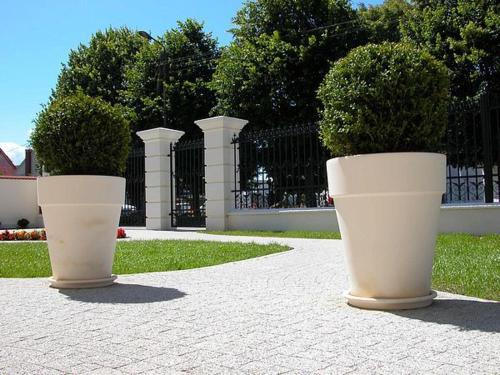 two large white pots with plants in them on a sidewalk at Residenz Selena in Ustka