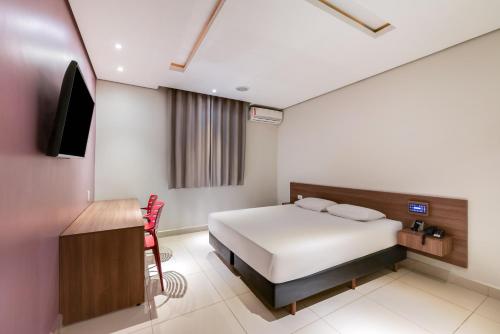 a bedroom with a bed and a tv and a desk at Plaza Motel in Sorocaba