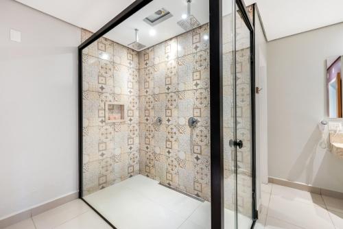 um chuveiro com uma porta de vidro na casa de banho em Plaza Motel em Sorocaba