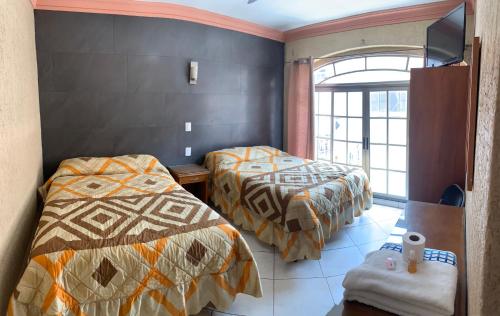 a hotel room with two beds and a window at Hotel Hacienda Salvador in San Juan de los Lagos