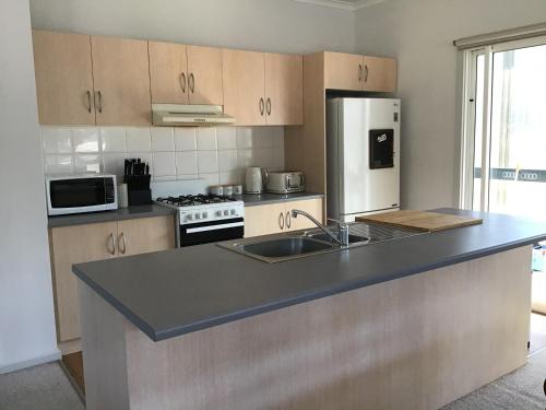 a kitchen with a counter with a sink and a refrigerator at Kangaroo Island Cabins in Kingscote