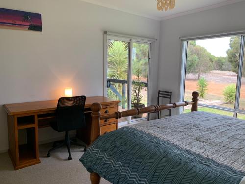 a bedroom with a desk and a bed and a desk and window at Kangaroo Island Cabins in Kingscote