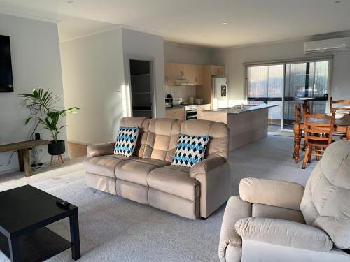 a living room with a couch and a kitchen at Kangaroo Island Cabins in Kingscote