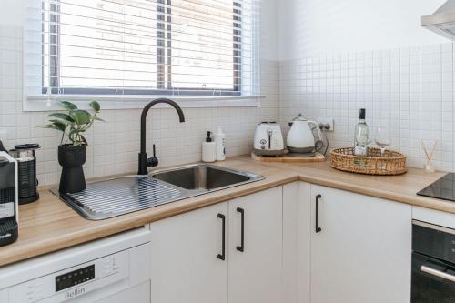 uma cozinha com armários brancos e um lavatório em Studio on Lewis Tiny House em Mudgee