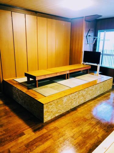 a bench in a room with a television on a wooden floor at Guest House Yun Terrace in Ishigaki Island