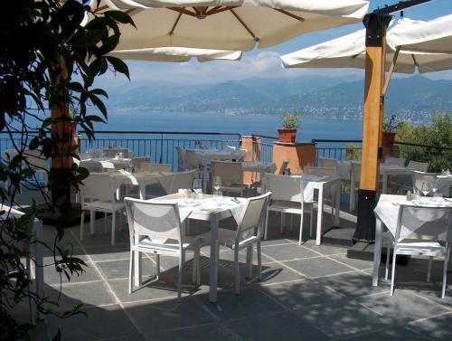 a restaurant with white tables and chairs and the ocean at Stella Maris Resort in Camogli