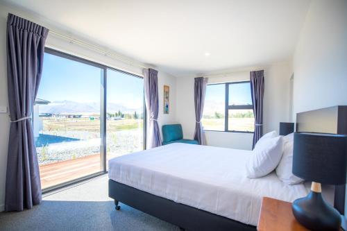 a bedroom with a large bed and a large window at Neptune - Lake Tekapo in Lake Tekapo