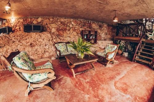 a living room with chairs and a table and a stone wall at Altos de Caño Hondo in Los Guineos Perdidos