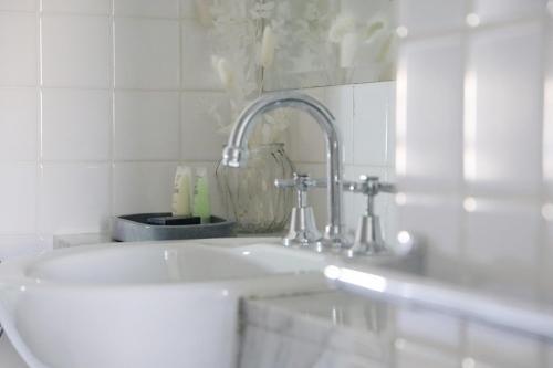 Baño blanco con lavabo y espejo en Hotel Collins, en Melbourne