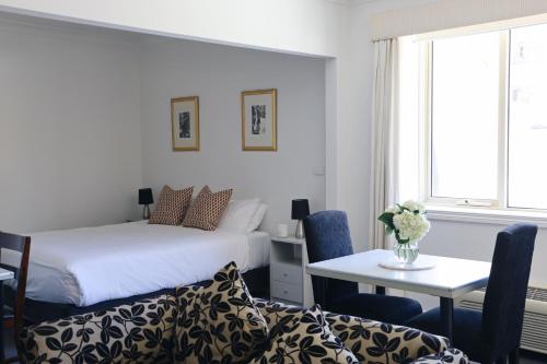 1 dormitorio con cama, mesa, mesa y sillas en Hotel Collins, en Melbourne