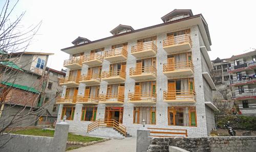 a large white building with wooden balconies on it at Treebo Trend Dev With Valley View, Mall Road in Manāli