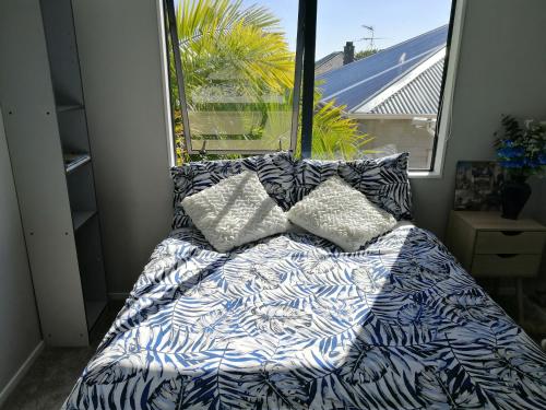 een bed met kussens in een kamer met een raam bij Sunny Sandringham SkyTower Views Close to City in Auckland