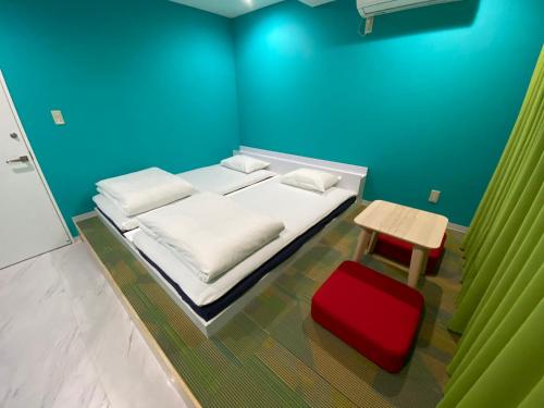 a blue room with a bed and a red stool at Hostel Anchorage in Kobe