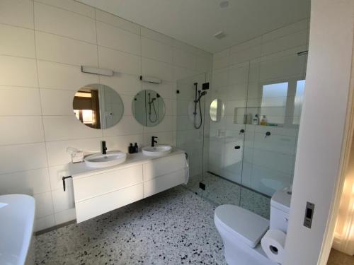 a white bathroom with two sinks and a shower at La Casétta in Leura