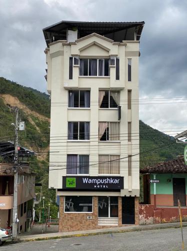 a tall white building with a sign on it at Hotel Wampushkar in Zamora