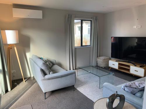 a living room with two chairs and a flat screen tv at Stylish Oasis in central city in Christchurch
