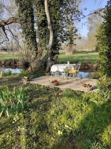 a table and chairs sitting on a patio next to a pond at gîte " jardin peyrona" visite zoo beauval et châteaux de Loire in Beaulieu-lès-Loches