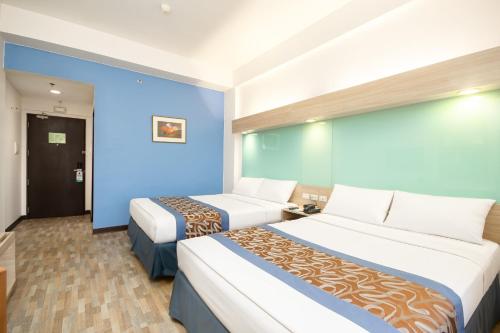 a hotel room with two beds and a blue wall at Microtel by Wyndham Mall of Asia in Manila