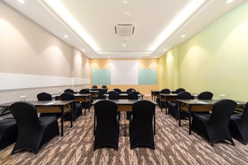 a conference room with tables and chairs and a projection screen at Zest Harbour Bay Batam by Swiss-Belhotel International in Nagoya