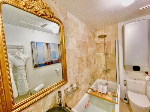 W łazience znajduje się lustro, umywalka i wanna. w obiekcie MonCoeur, maison et jardin à 700 m des Hospices de Beaune w mieście Beaune