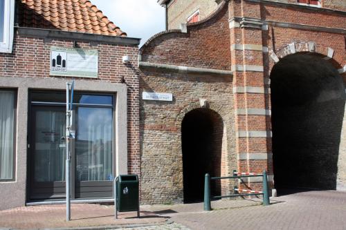 a brick building with two arches on it at De Stadspoort appartementen in Aardenburg