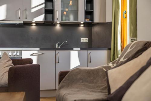 a kitchen with white cabinets and a sink and two chairs at Hotel Das Gastein - ganzjährig inklusive Alpentherme Gastein & Sommersaison inklusive Gasteiner Bergbahnen in Bad Hofgastein