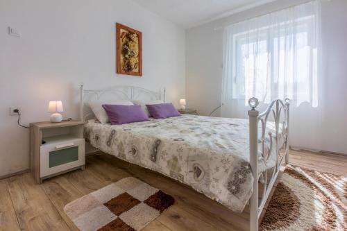 a white bed with purple pillows in a bedroom at Francisko in Grižane