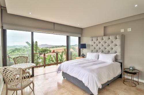 a bedroom with a large bed and a balcony at 6 Crystal Cove Zimbali 5 Bedroom ZPS6 in Ballito