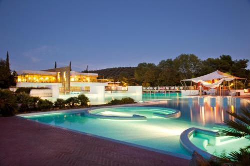 a swimming pool at night with a building in the background at Camping Village Rocchette in Castiglione della Pescaia