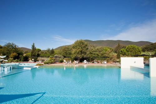a swimming pool with blue water and mountains in the background at Camping Village Rocchette in Castiglione della Pescaia