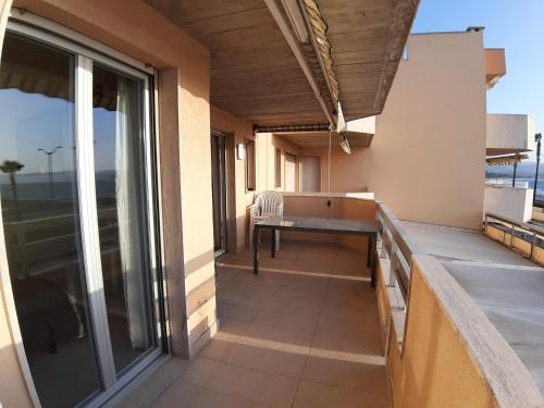 een balkon met een tafel en uitzicht op de oceaan bij appartement Cavalaire face à la mer in Cavalaire-sur-Mer