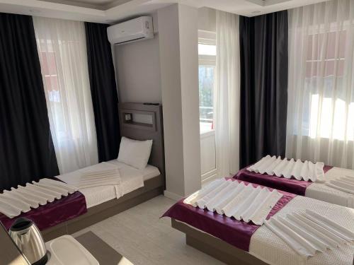 two beds in a room with two windows at Konyaaltı HOTEL in Antalya