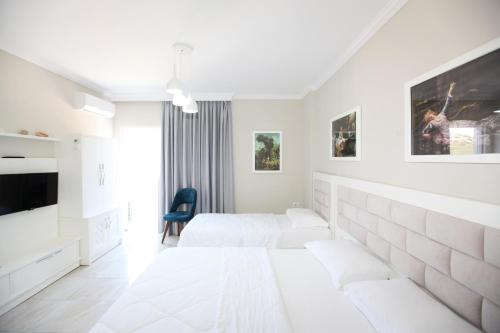 a white bedroom with two beds and a tv at Hotel Mare in Ksamil